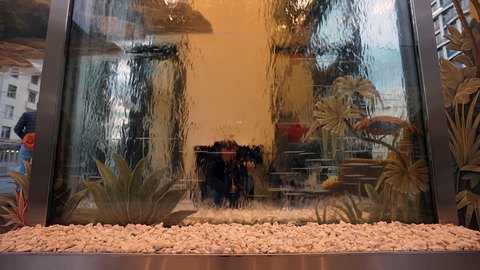 Нижняя часть водопада с каменной засыпкой, отражениями и рисунком птицы на стене